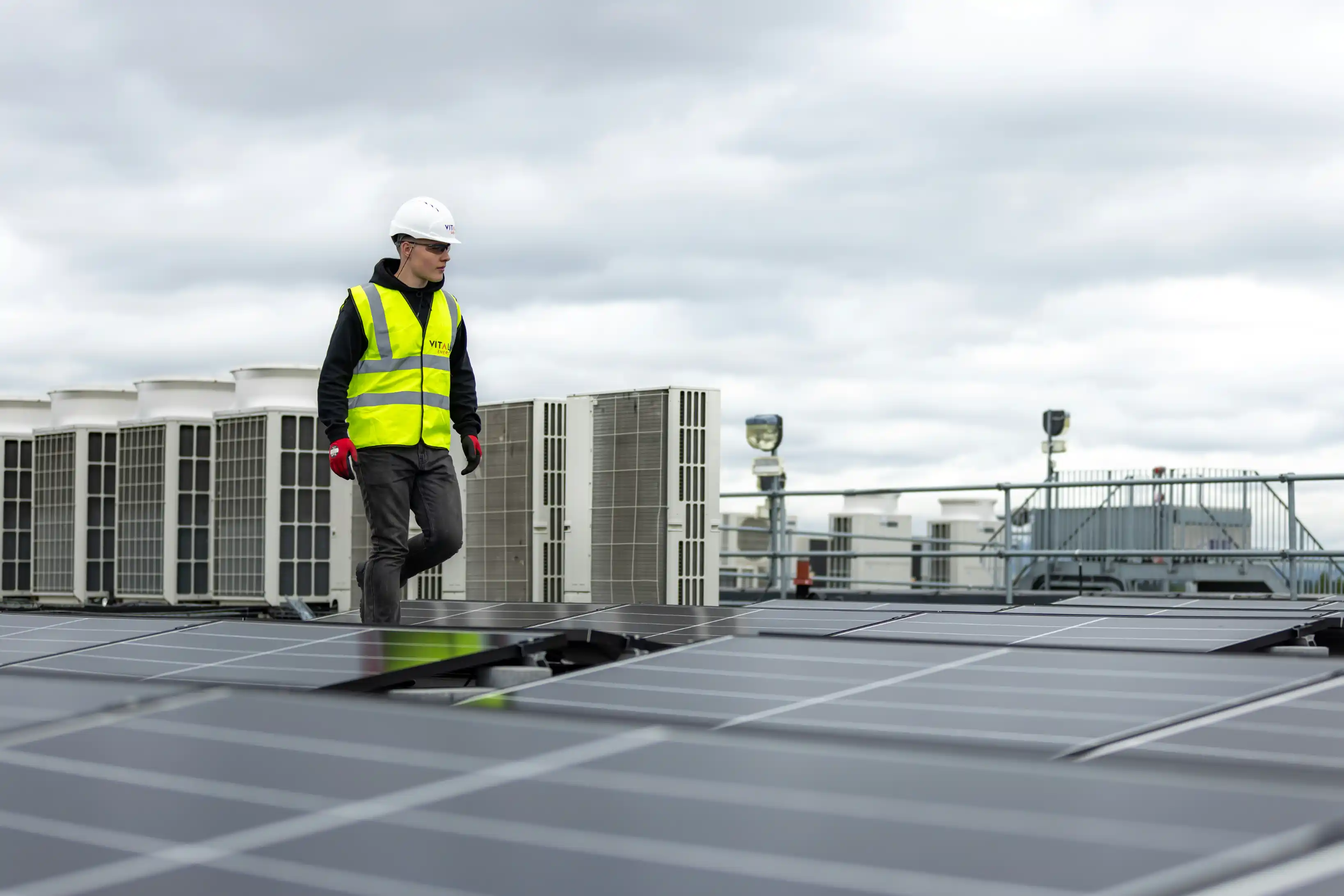Technician on a commercial rooftop beside building mechanical equipment