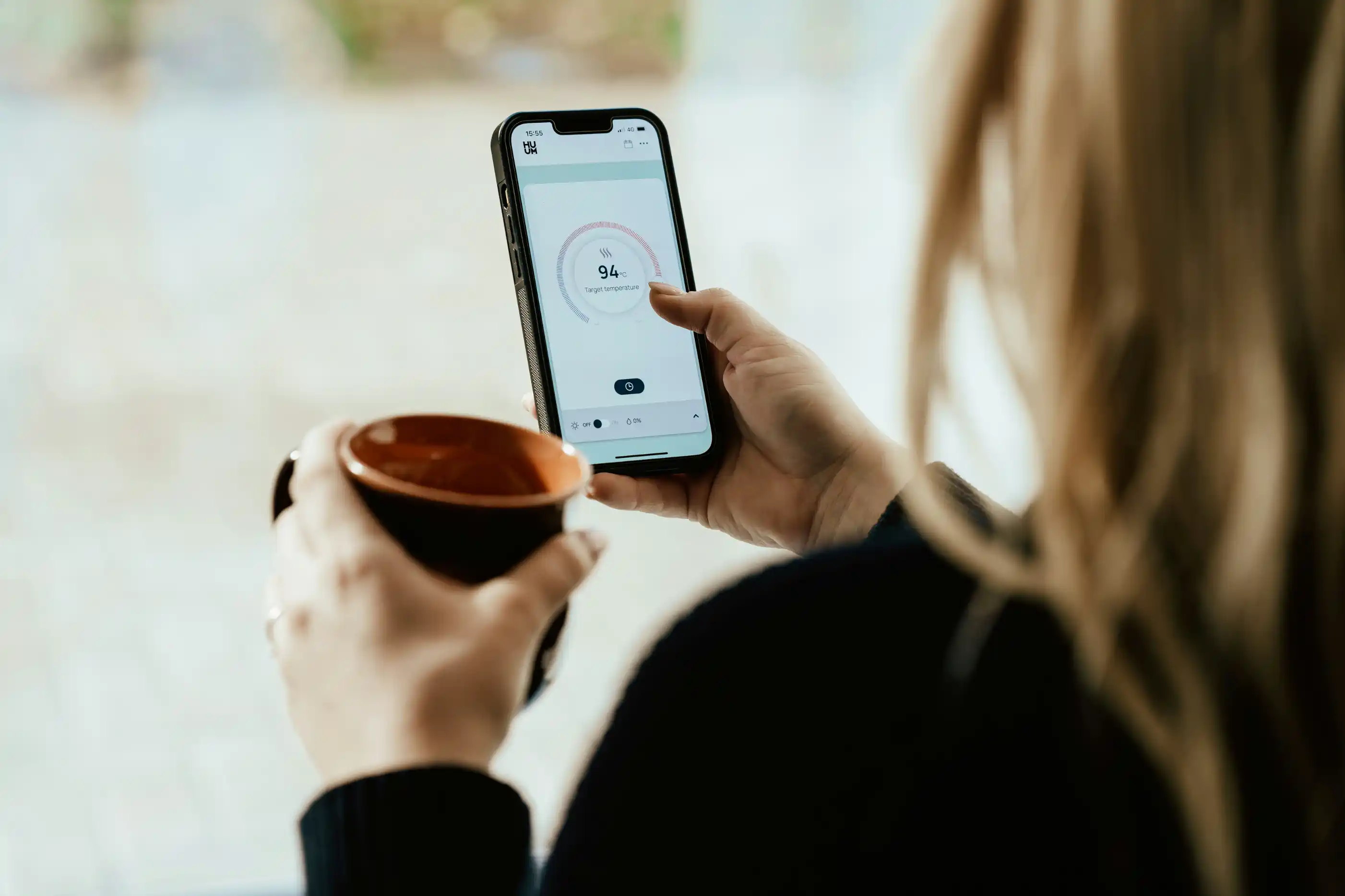 A woman holding a coffee and scrolling on her smartphone